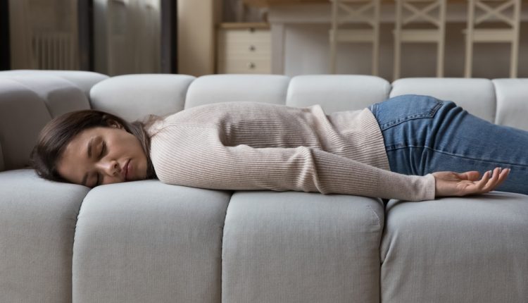 Tired,Calm,Young,Woman,Resting,On,Spacious,Sofa,In,Home